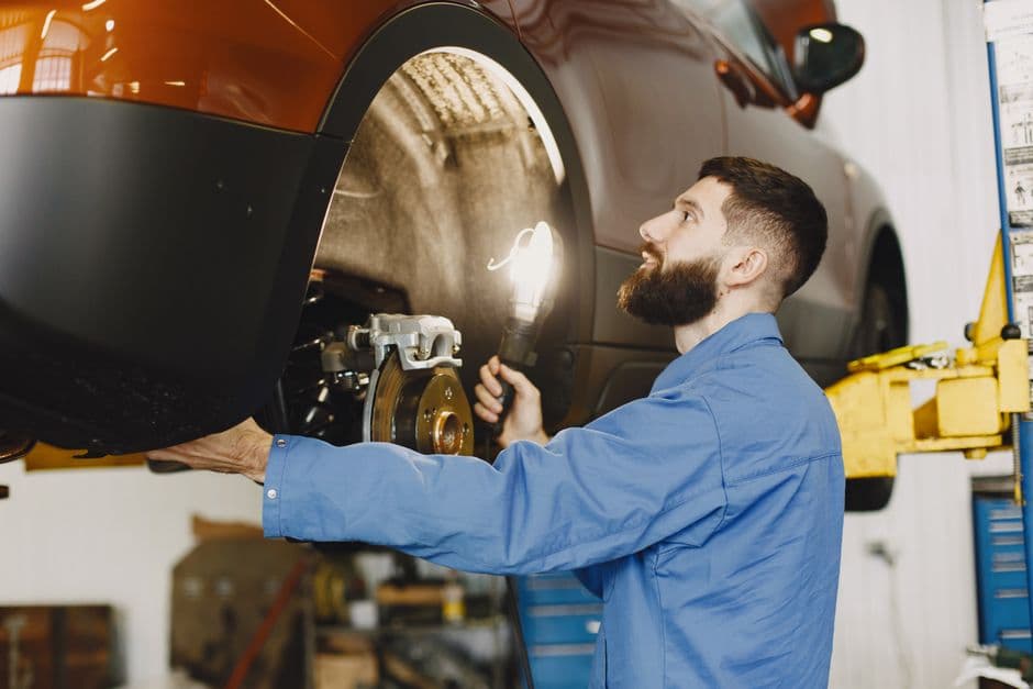 Mechanic inspecting car brakes during a vehicle safety inspection