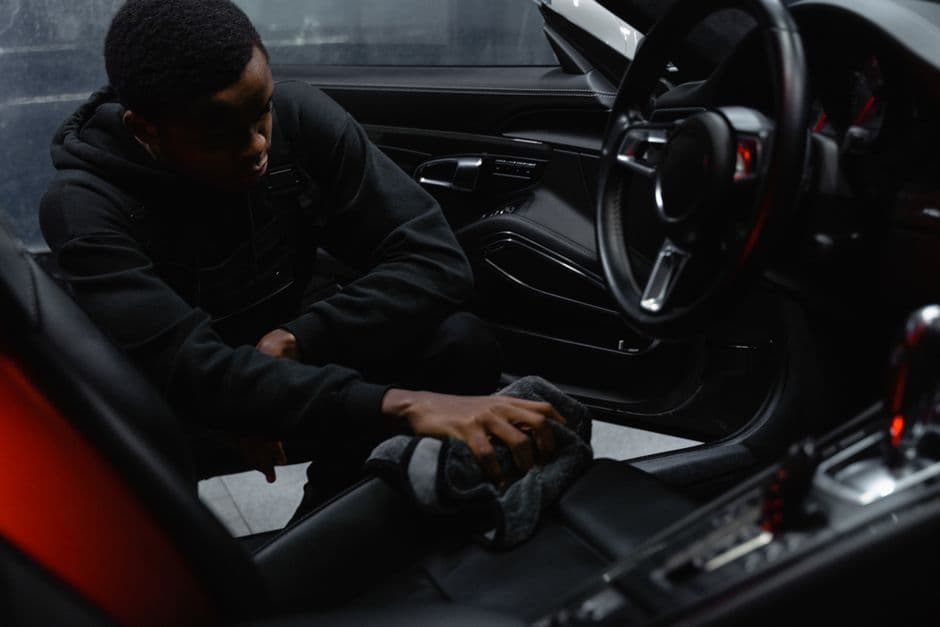 Detailer wiping down a car's leather interior as part of routine seat maintenance