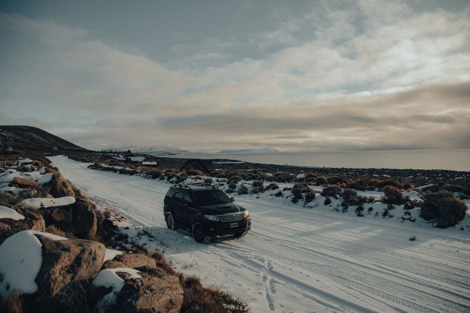 SUV driving on a snow covered road after winter car maintenance and tire checks
