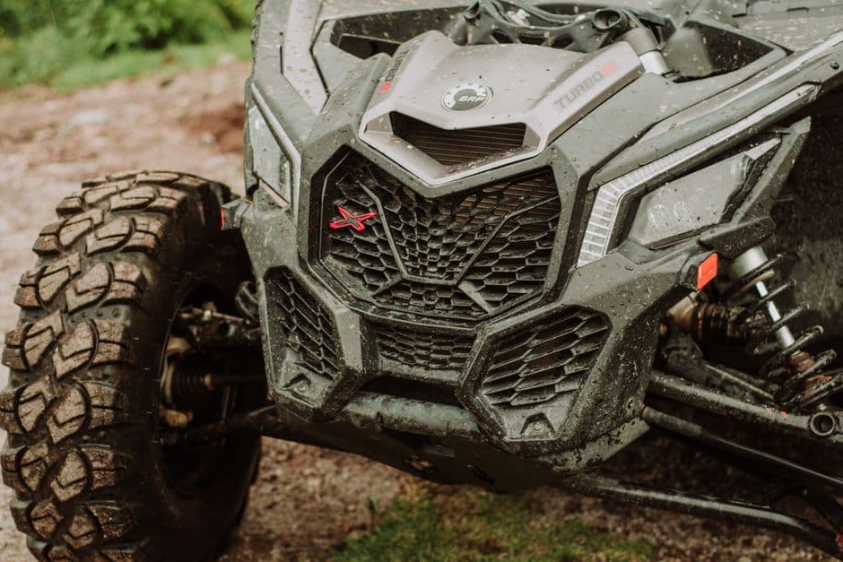 Close-up of a muddy ATV tire and suspension after off-road riding