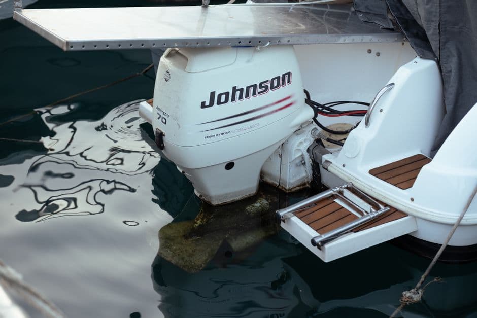 Close-up of an outboard boat motor on calm water during routine maintenance