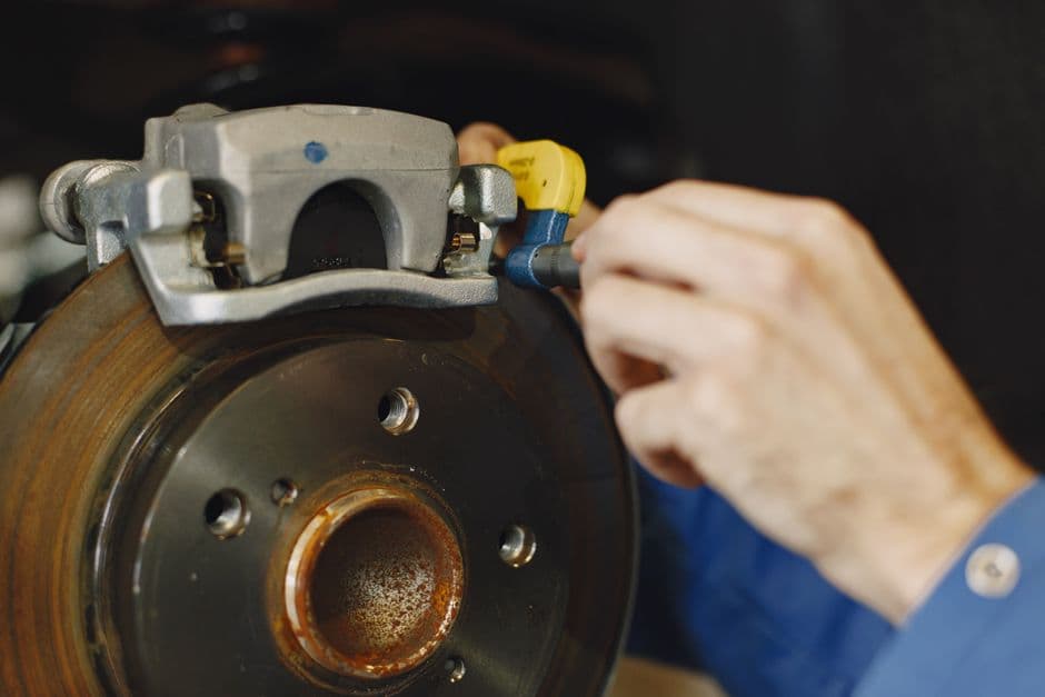 Mechanic inspecting a car's disc brake system for wear during maintenance