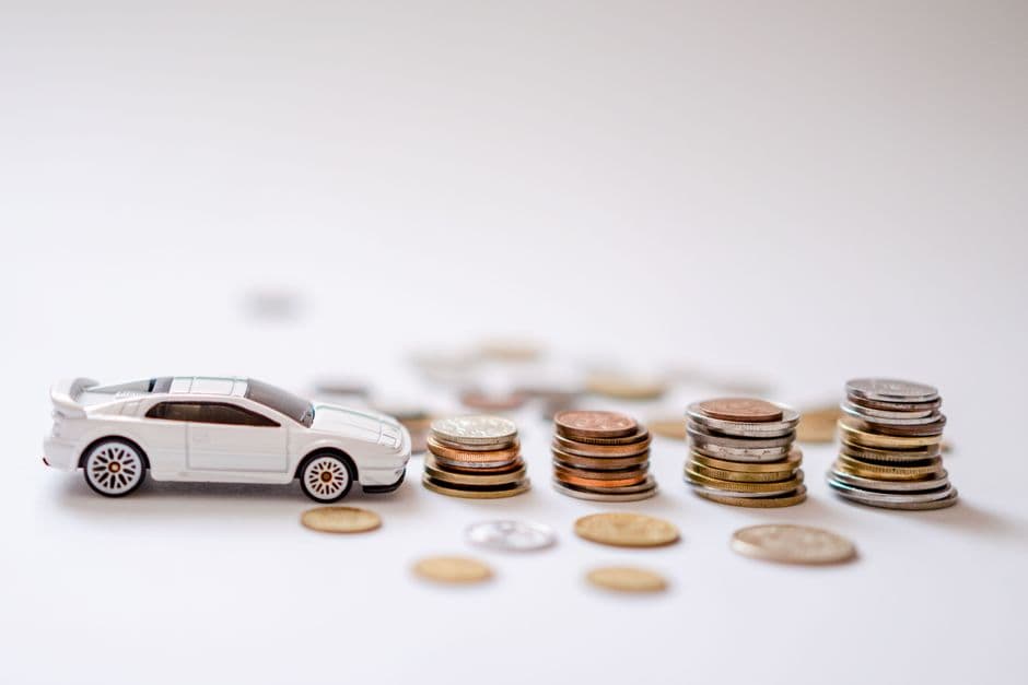 Toy car next to a stack of coins representing a car maintenance budget