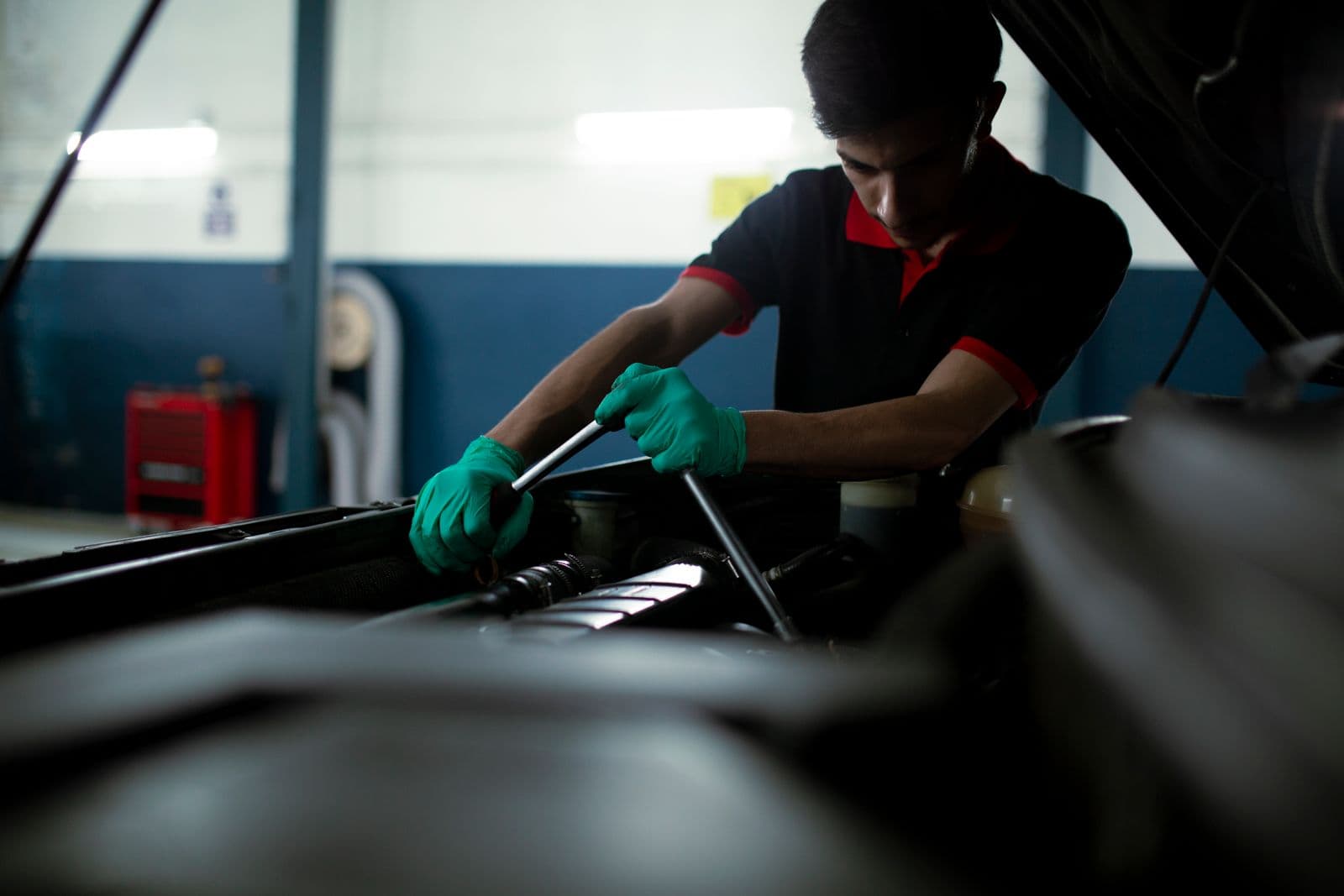 Mechanic using a torque wrench on an engine, the kind of job worth recording in a vehicle maintenance log