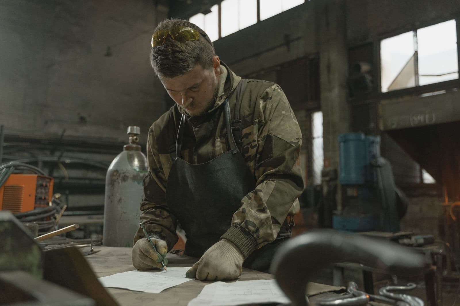 Mechanic writing maintenance notes for a car service log in a workshop
