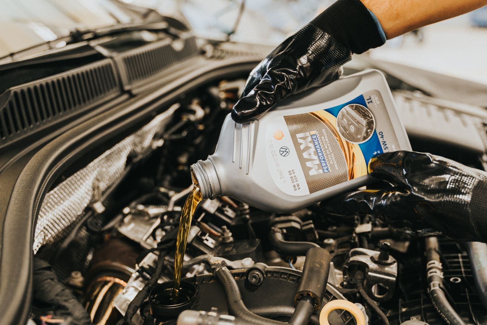 Mechanic pouring fresh engine oil during a scheduled car maintenance service