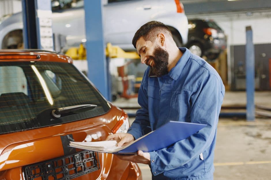 Auto mechanic in a service garage holding paperwork, the kind of documentation worth keeping with a recall repair