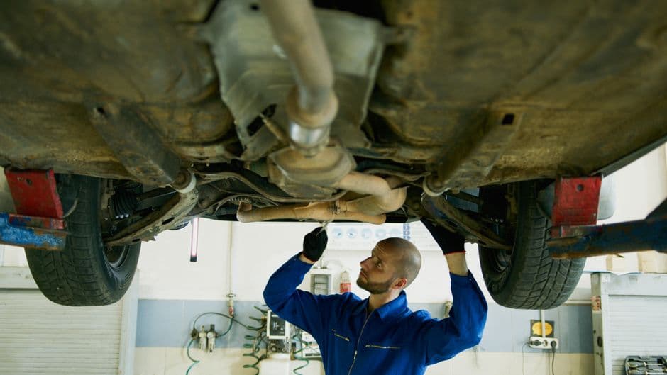 Mechanic examining the underside of a car's suspension for worn components