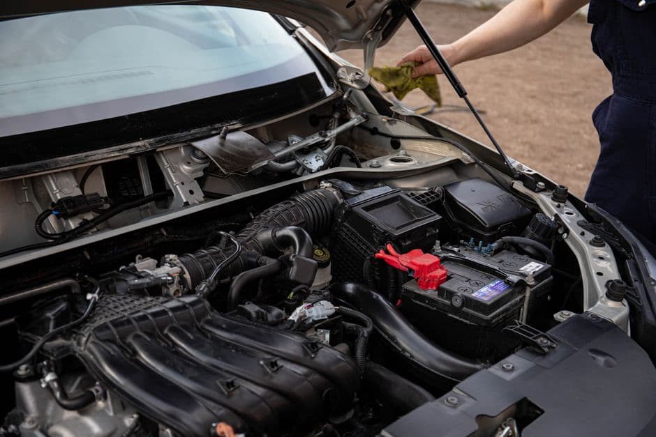Mechanic inspecting the engine bay and battery during routine charging system maintenance