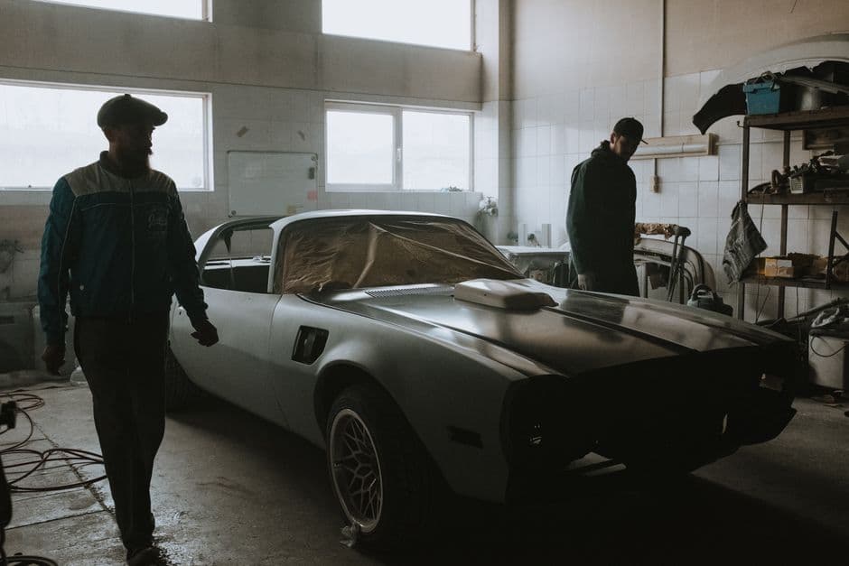 Mechanics working on a vintage car restoration project in a home garage