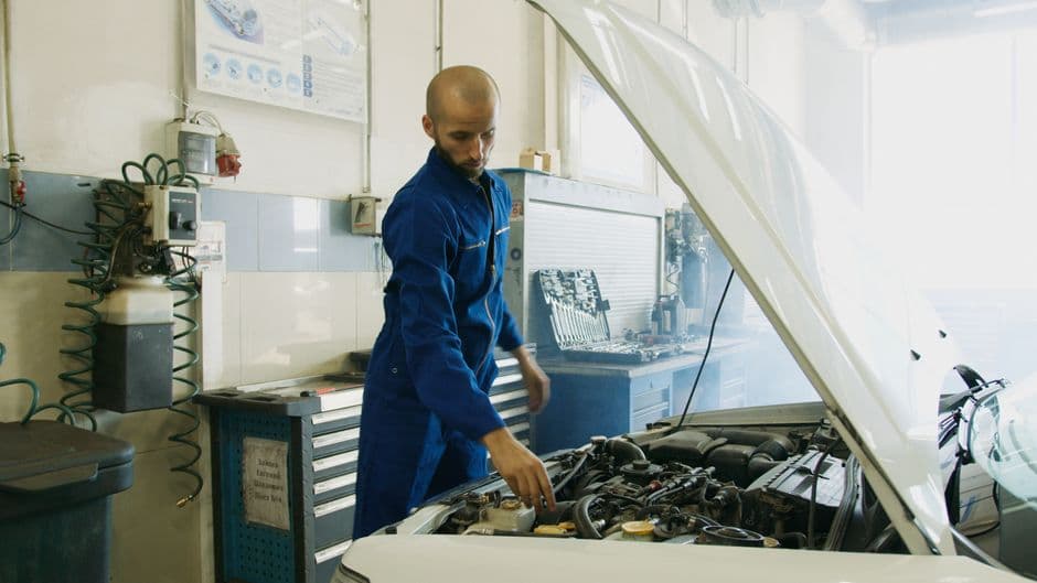 Mechanic inspecting an engine for wear caused by deferred car maintenance