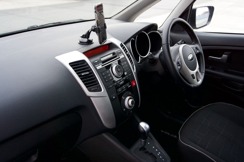 Car dashboard interior showing a mounted device near the windshield, similar to a dash cam mounting position