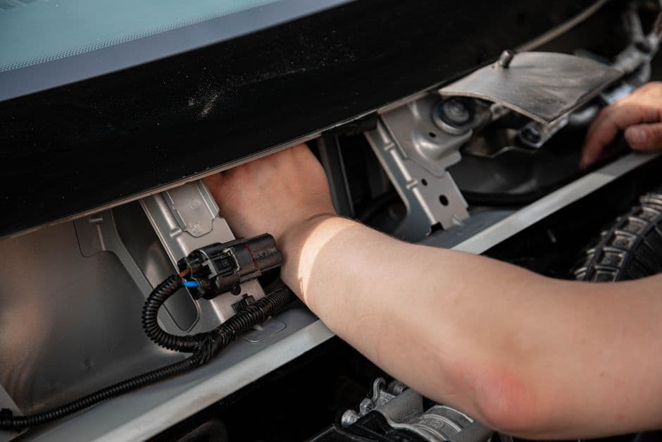Mechanic's hands working on a car's electrical wiring during a security system installation