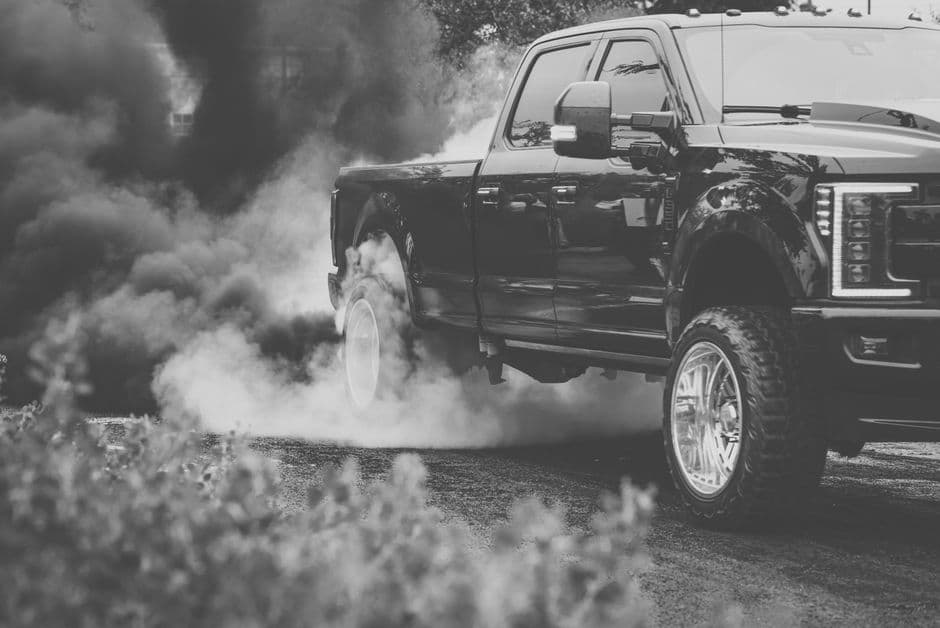 Black diesel pickup truck exhaust releasing dark smoke, illustrating why diesel emissions system maintenance matters