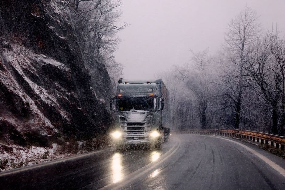 Diesel truck driving through snow on a mountain road, the conditions diesel truck winter maintenance prepares for
