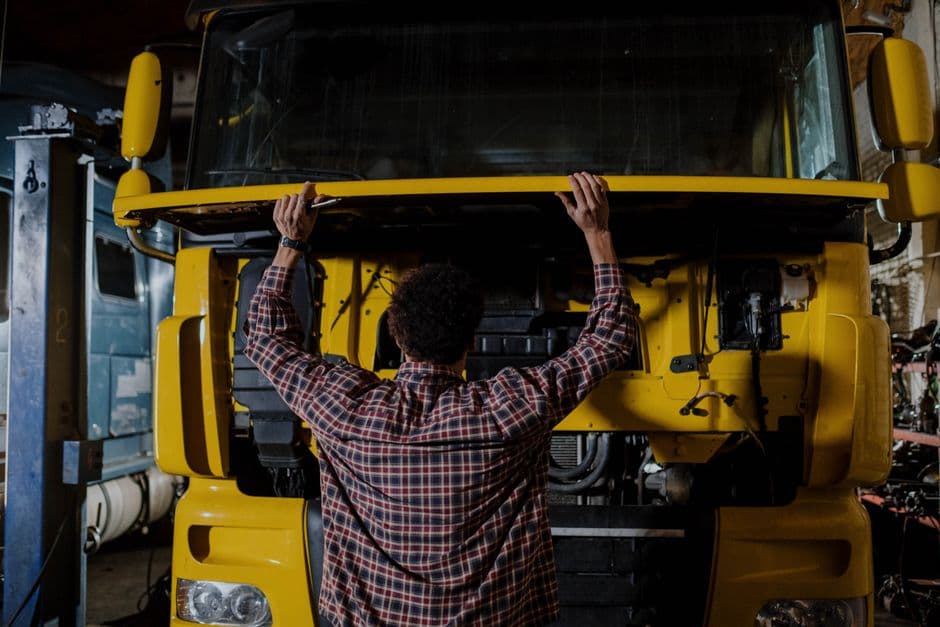 Mechanic inspecting a diesel truck engine, the kind of cold weather check for batteries, glow plugs, and fuel filters