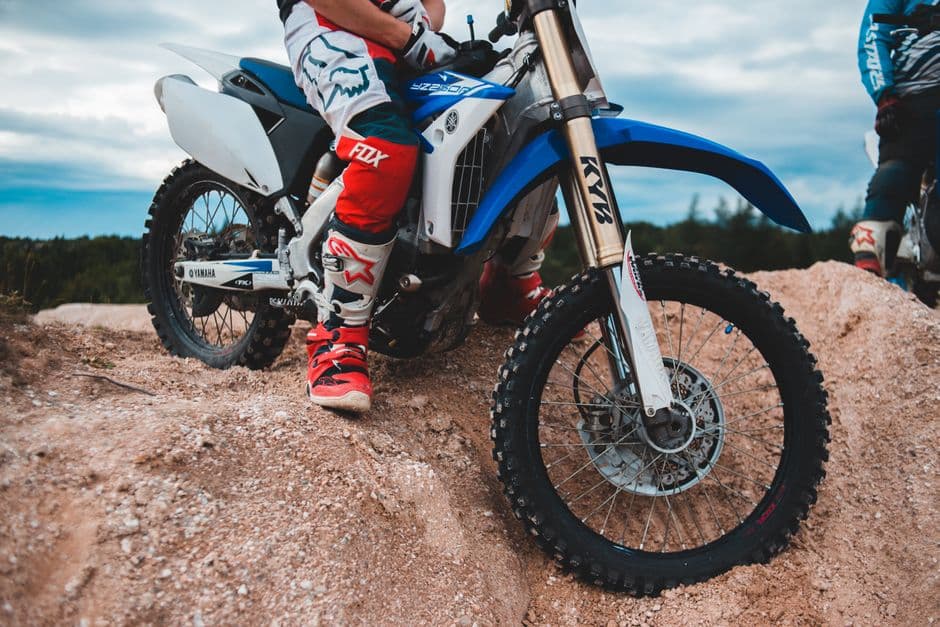 Dirt bike and rider resting on a sandy off-road trail during a break in riding