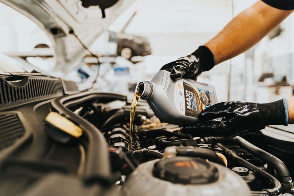 Person pouring engine oil during a DIY oil change, the kind of service that raises warranty questions