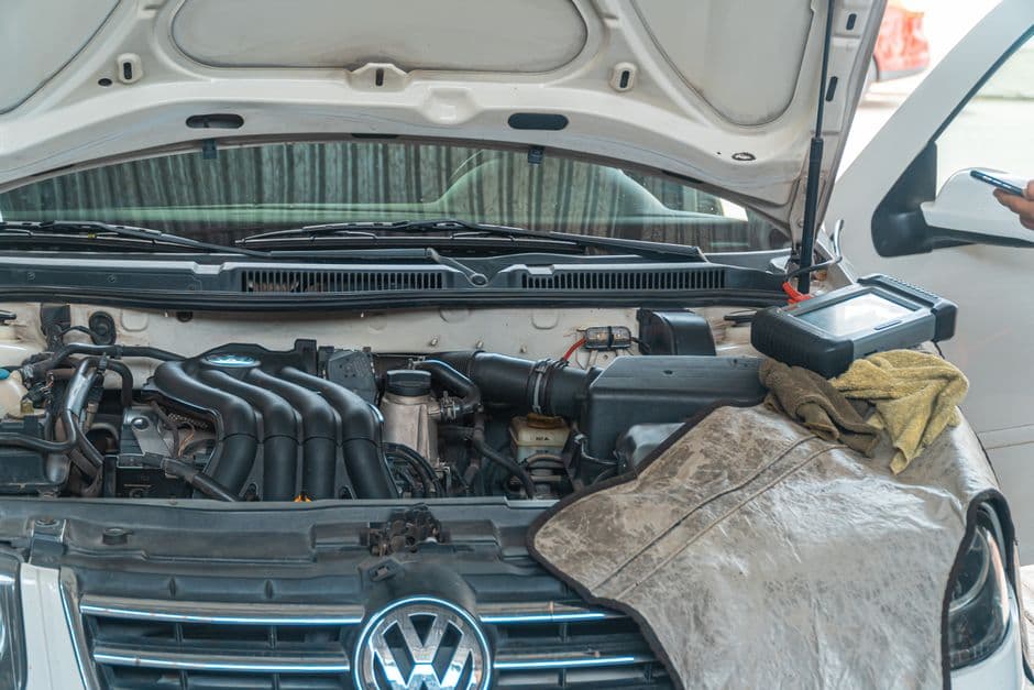 Laptop connected to a car's engine bay for ECU tuning and diagnostic work