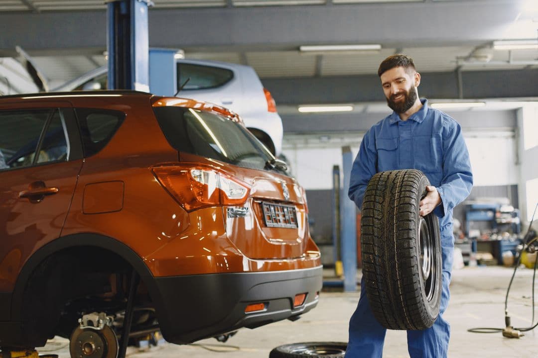 A mechanic servicing a tire, the wear item that matters most in electric car maintenance