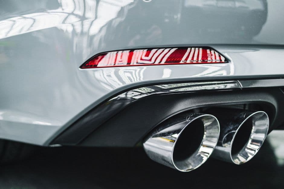 Close-up of a car's muffler and exhaust pipe showing metal surface condition