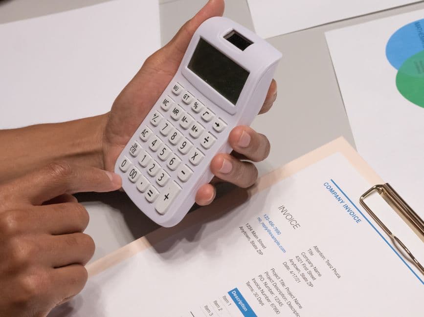 Calculating fleet repair cost from a service invoice with a calculator and notepad
