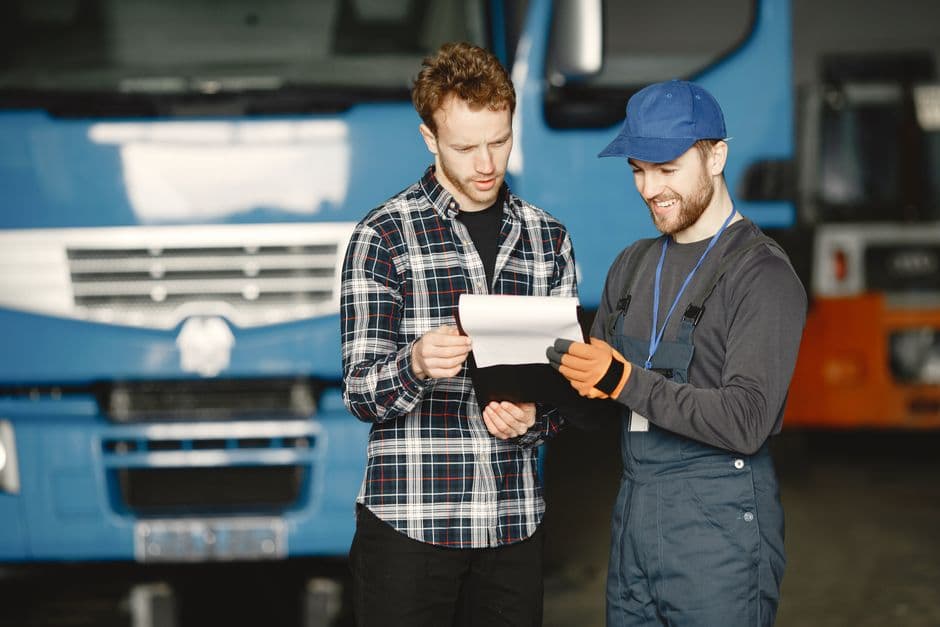 Two people reviewing fleet vehicle maintenance documents in a garage