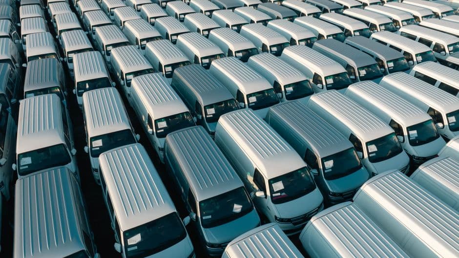 Aerial view of a small business fleet of vans parked in a lot, the kind of fleet a new vehicle joins through an onboarding checklist