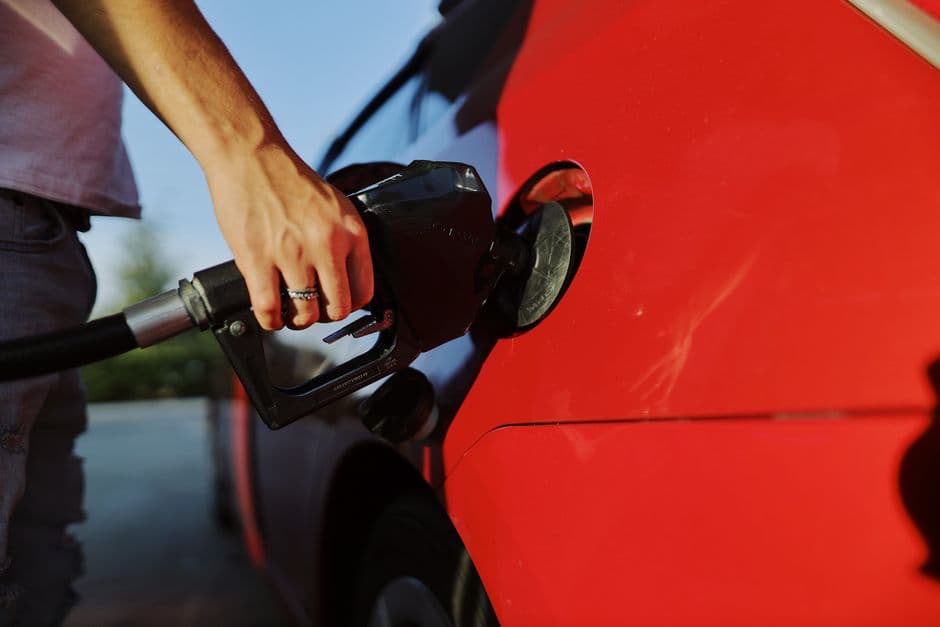 Person refueling a car at a gas station during the day, tracking fuel costs and mileage