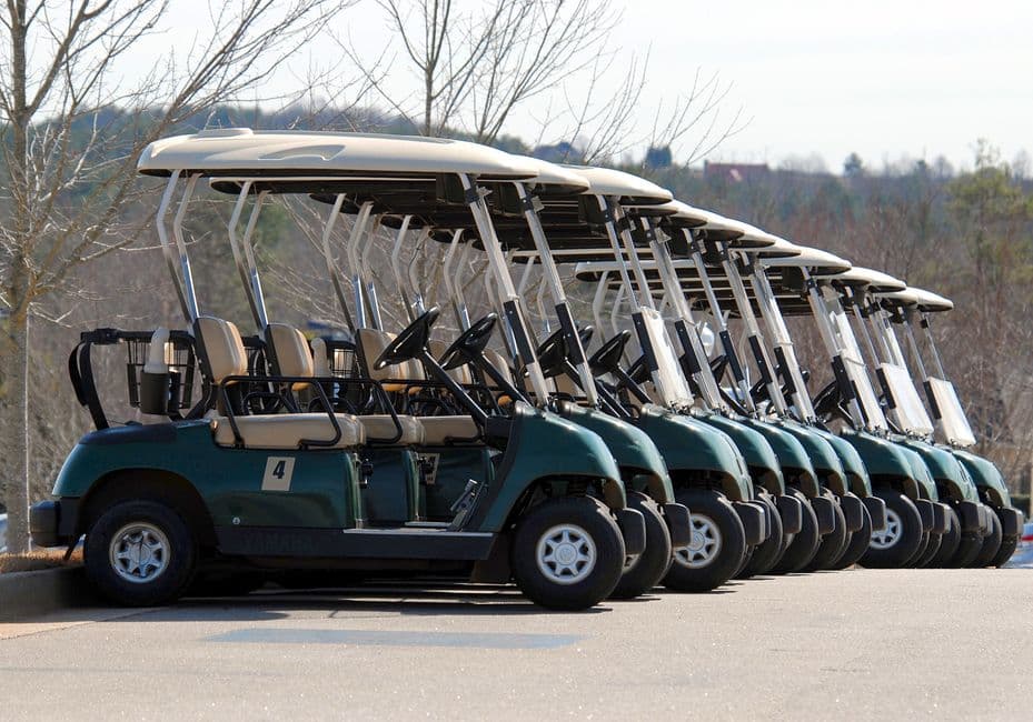 Row of golf carts parked on a course before a maintenance check