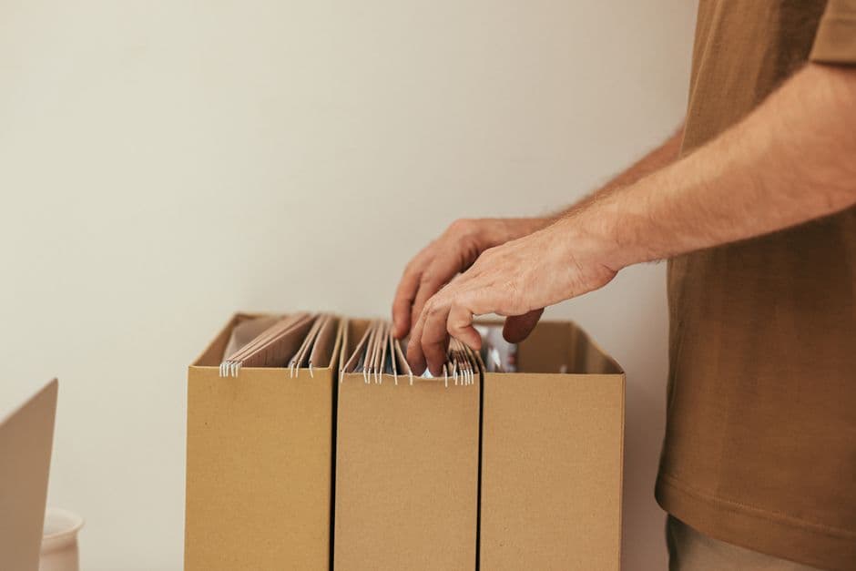 Person organizing paper maintenance receipts and files into boxes before scanning