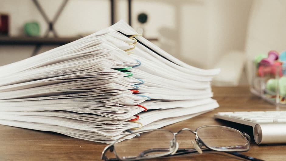 Stack of paper maintenance receipts on a desk ready to be scanned and organized