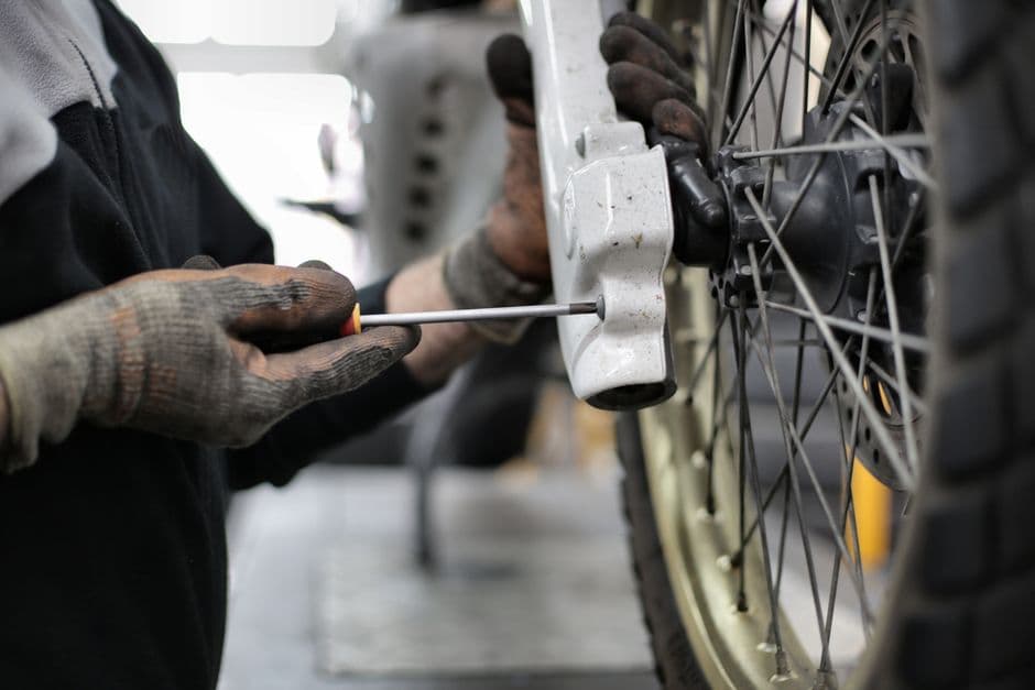 Mechanic servicing a motorcycle rear wheel and tire with a wrench
