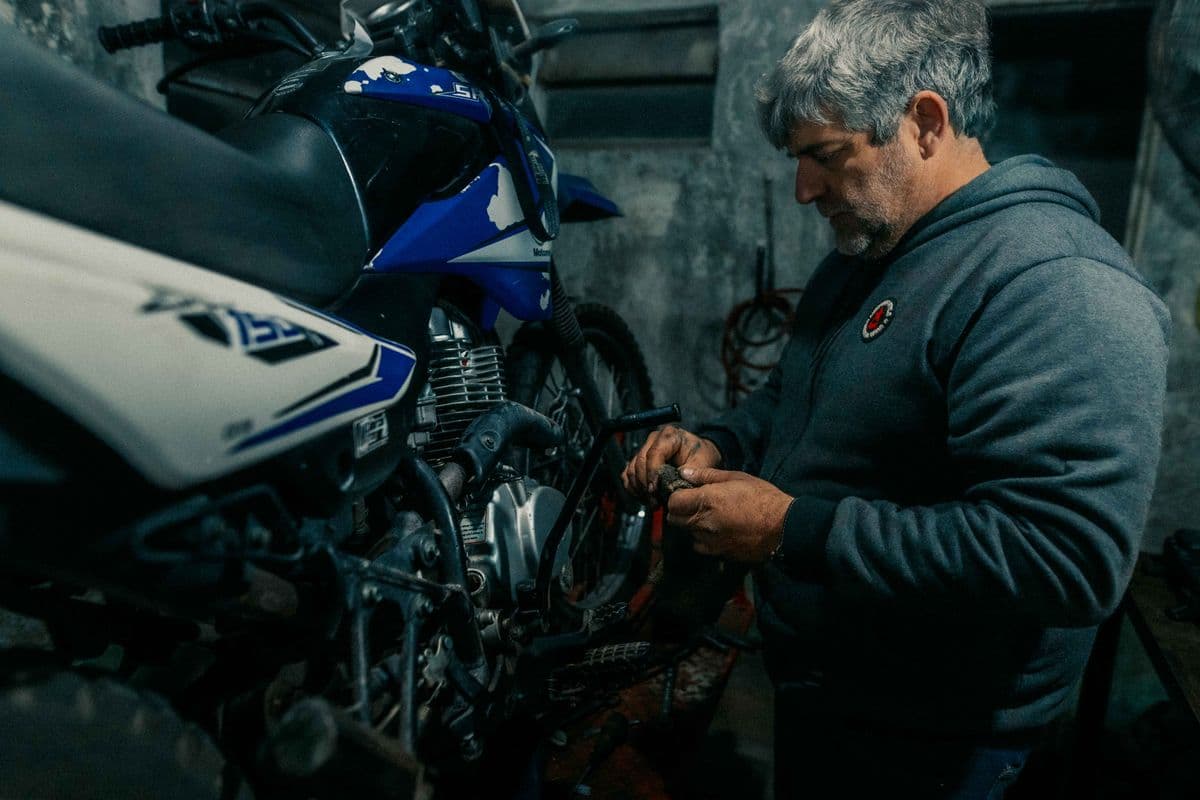 Rider performing motorcycle maintenance on a bike in a home garage