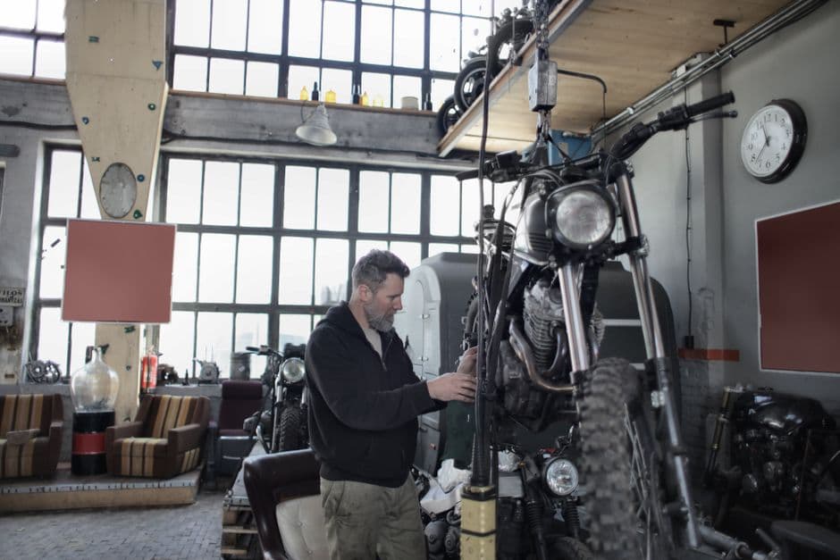 Mechanic performing a spring motorcycle startup inspection in a workshop