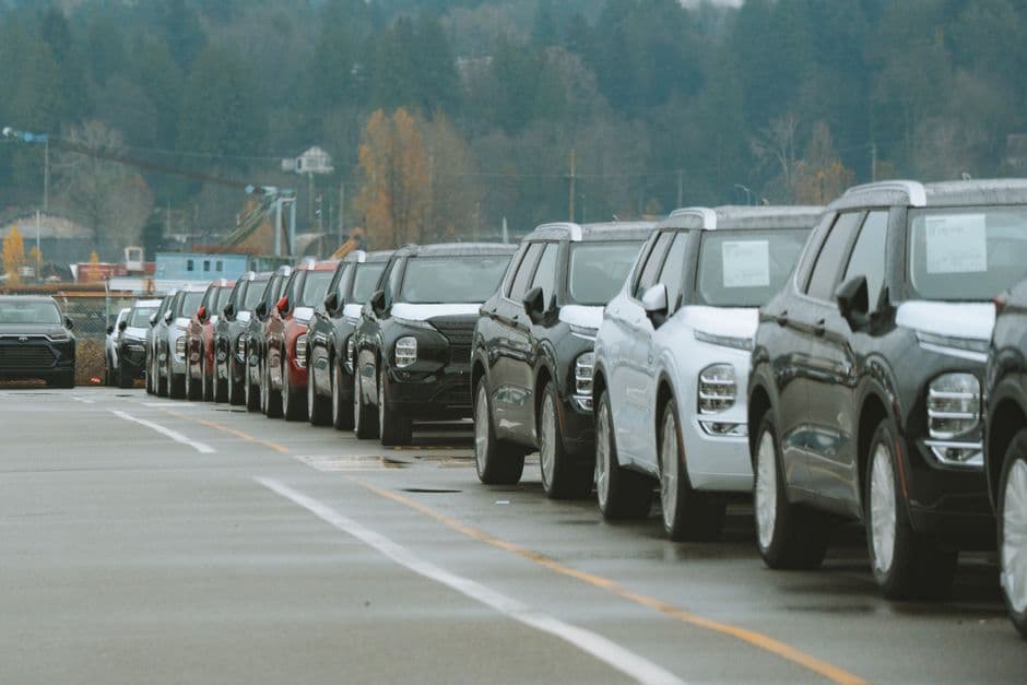 Row of new cars parked at a dealership lot before delivery