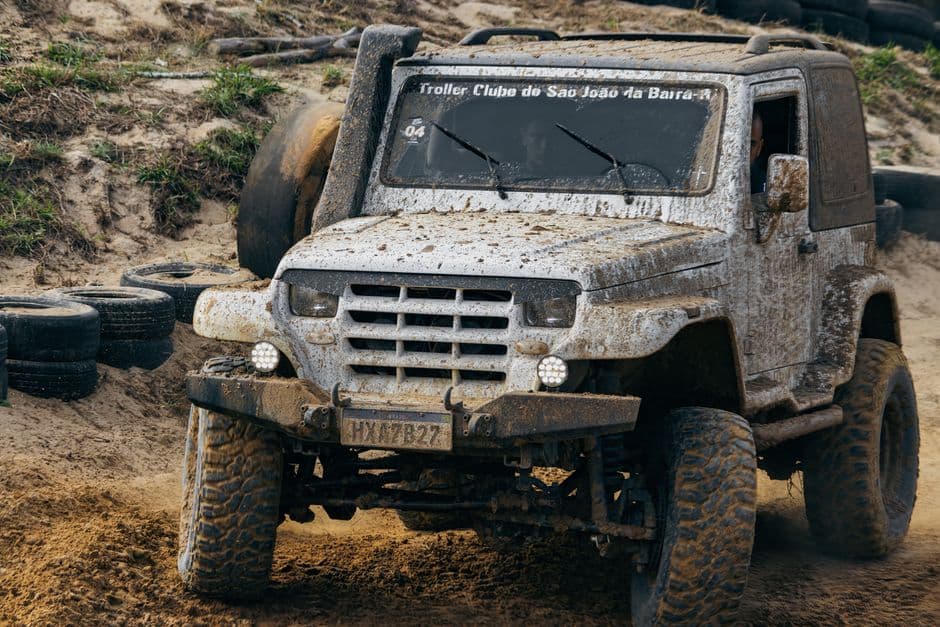 Muddy 4x4 truck navigating an off-road trail, the kind of use that shortens maintenance intervals