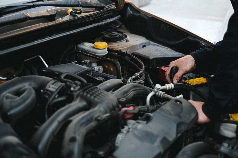 Mechanic's hands working under the hood near the power steering pump and belt