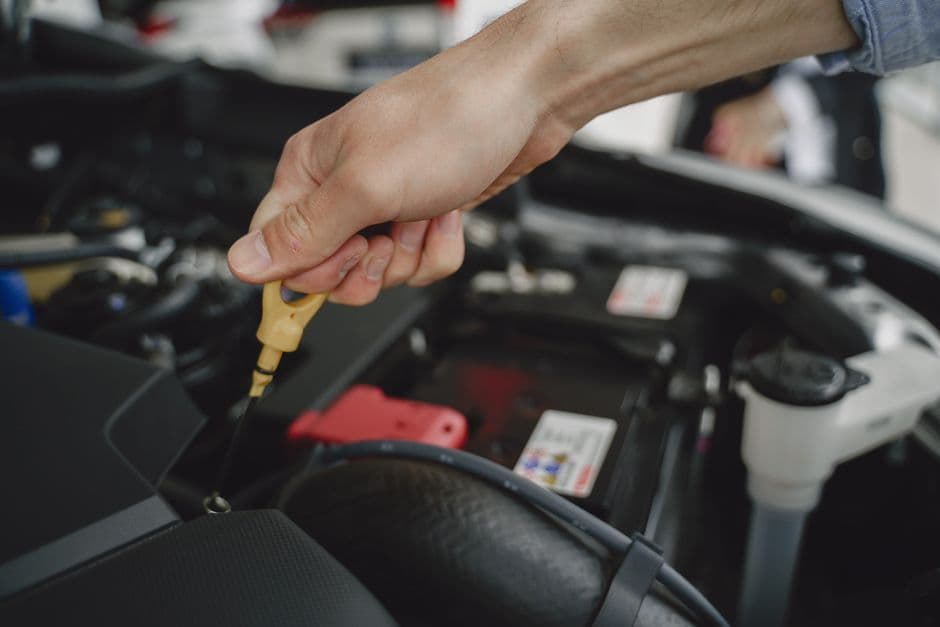 Hand checking the engine oil dipstick as part of preventive car maintenance