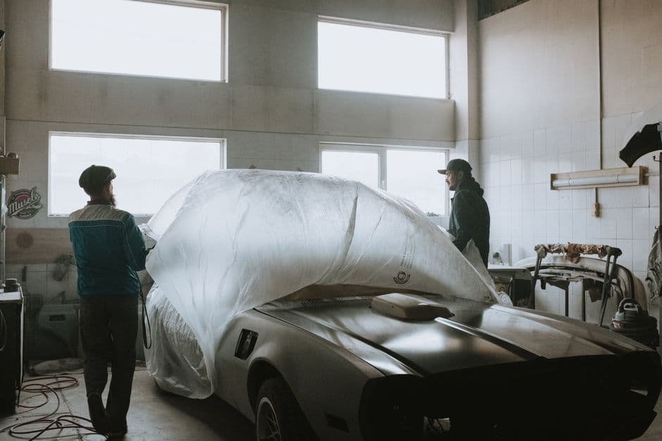 Two mechanics working on a project car restoration in a home garage