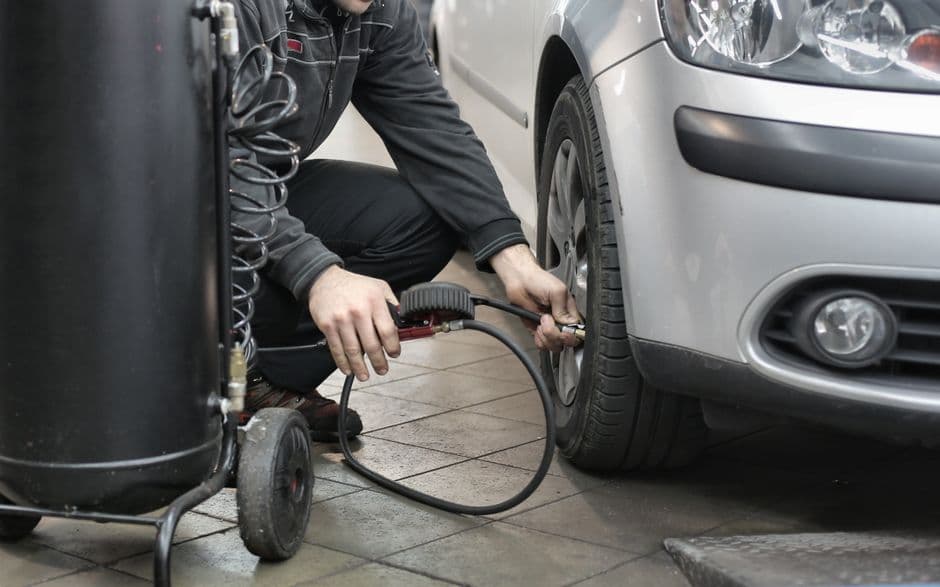 Checking and adjusting car tire pressure with a gauge before a long road trip