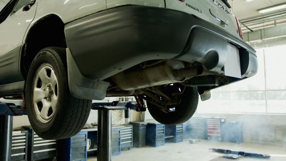 Car elevated on a lift in an auto repair shop for an undercoating inspection