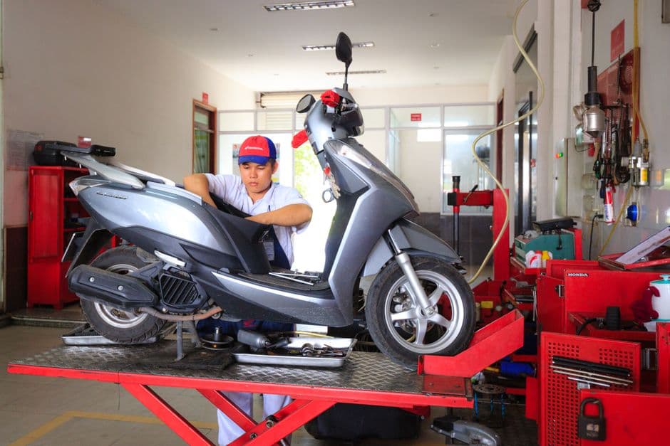 Mechanic working on a moped in a well-equipped workshop during a service appointment