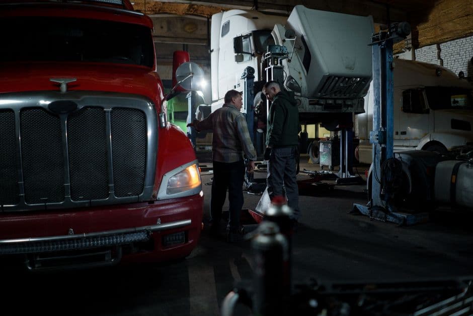 Technicians performing preventive maintenance service on a truck in a shop
