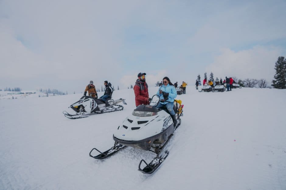 Riders crossing a snowy field on snowmobiles during a winter ride