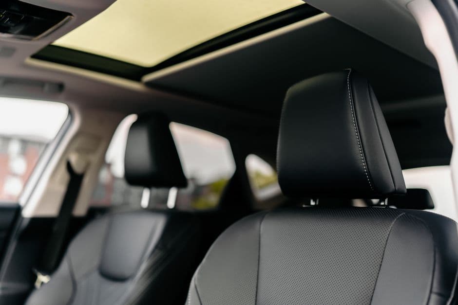 Car interior with leather seats and an open sunroof above the dashboard