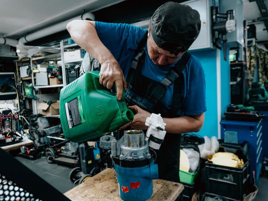 Mechanic adding fresh engine oil during a conventional oil change in a workshop