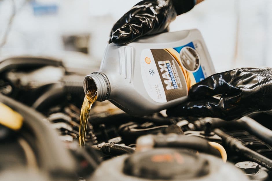Mechanic pouring synthetic motor oil into a car engine during an oil change