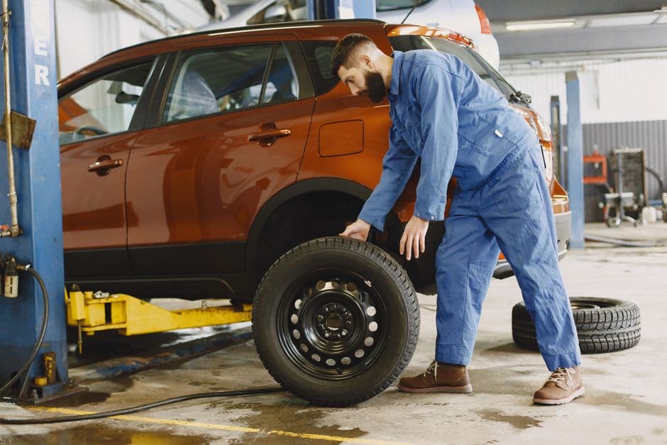 Mechanic performing a tire rotation on a raised vehicle in a garage