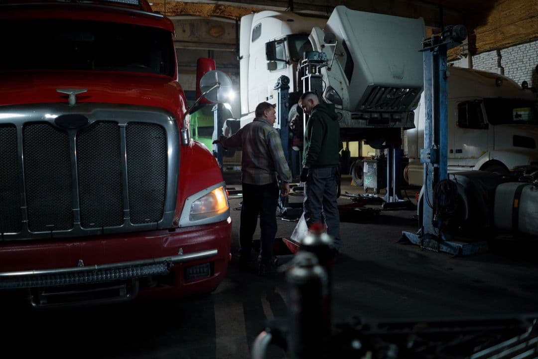 A mechanic performing truck maintenance on a diesel engine in a workshop